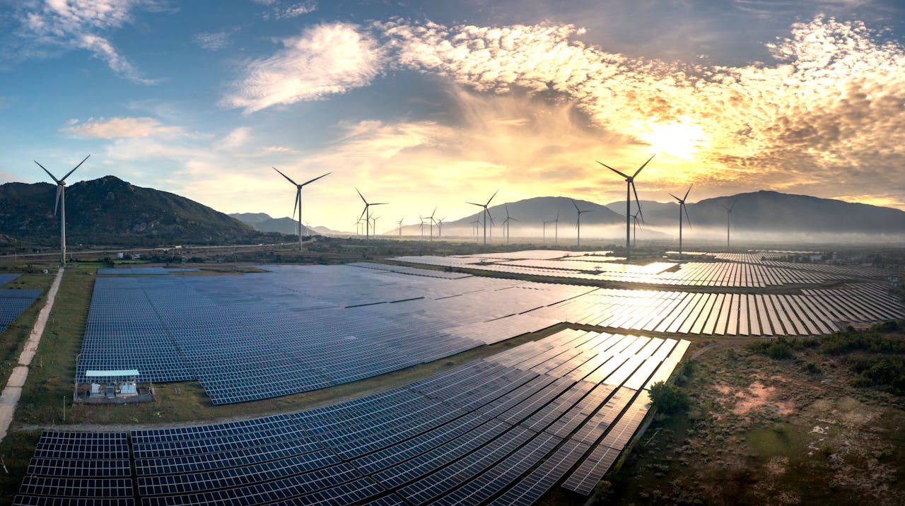 De energietransitie: naar een duurzaam energiesysteem Aerial photograph capturing solar panels and wind turbines under a stunning sunrise. Sustainable energy landscape.